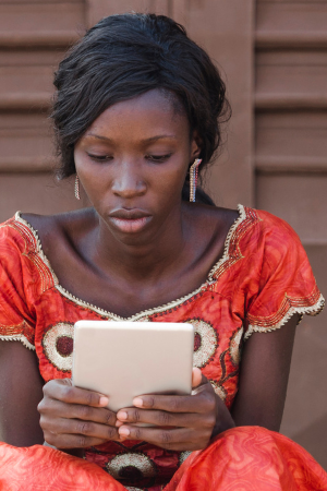 Street Shot of an African young woman working on business holding her tablet in a university in Bamako, Mali